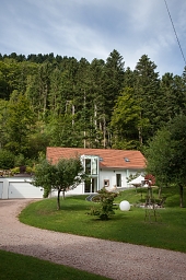Blick auf das Maison de l'Eau mit dem dahinterliegenden Wald Maison de l'Eau